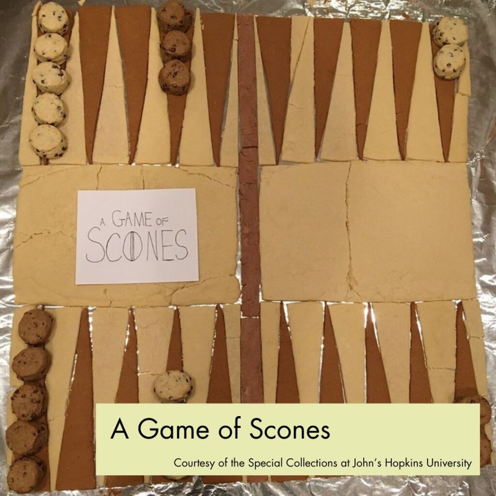 Photograph of a backgammon board made out of brown and tan scone triangles, with round scone pieces. In the bottom right, a green rectangle overlays the picture with black text, reading "A Game of Scones, Courtesy of the Special Collections at John's Hopkins University."